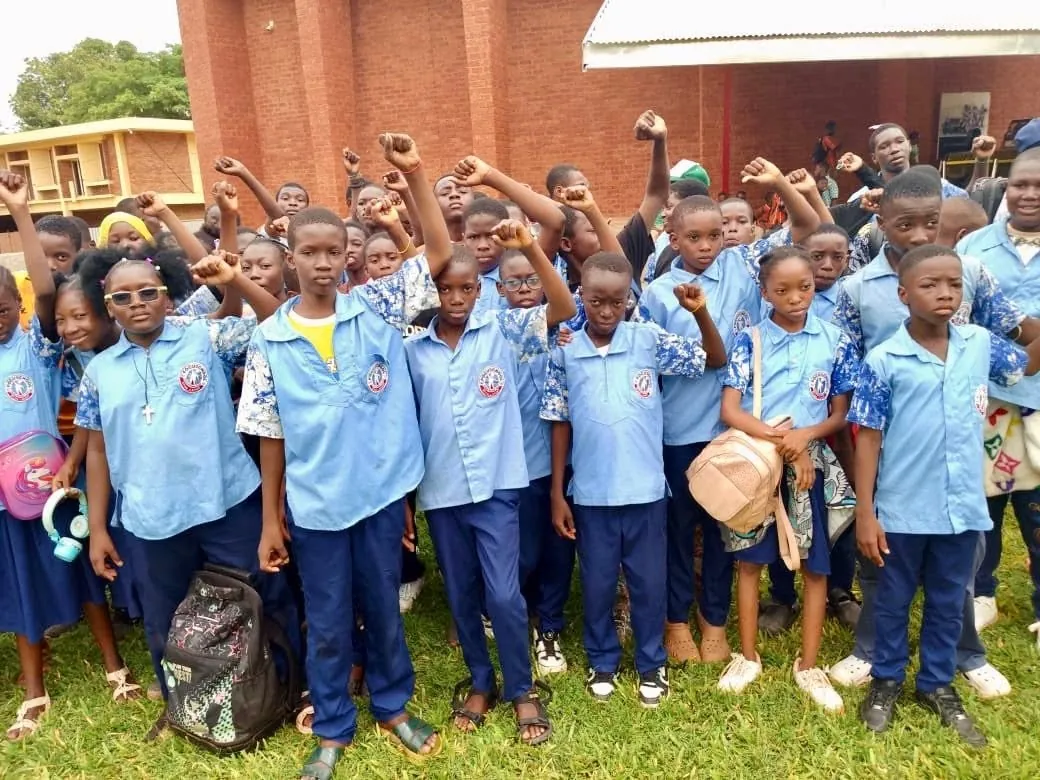 Élèves de Focus School en uniforme, poing levé dans la cour