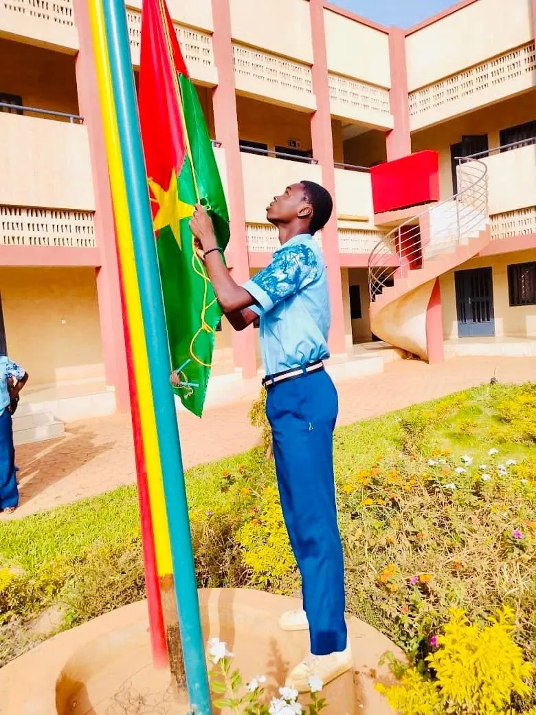 Élève de Focus School hissant le drapeau du Burkina Faso dans la cour